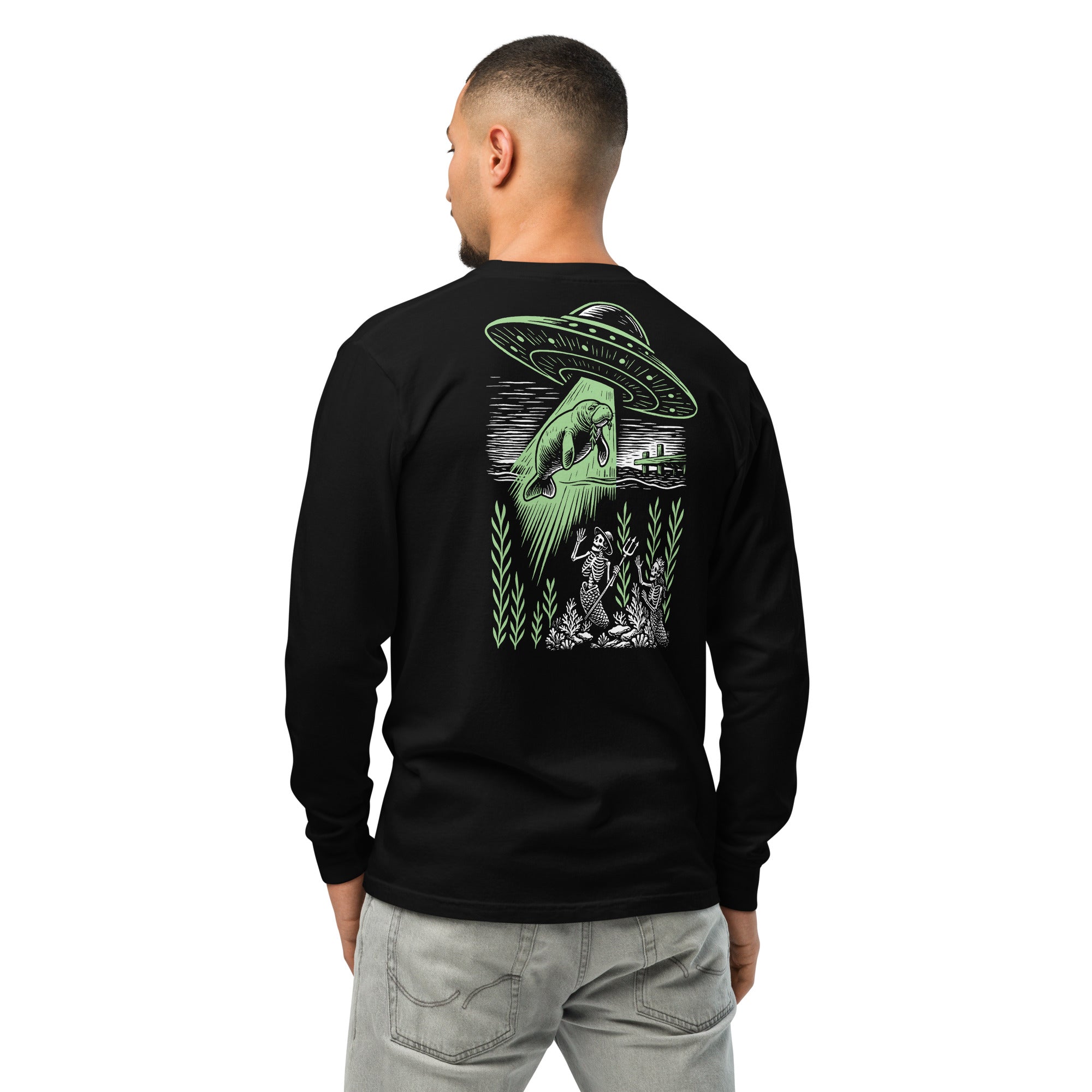 "Ocean Abduction" garment-dyed heavyweight long sleeve shirt, male model back view, featuring UFO abducting a manatee via tractor beam over skeleton mermaids design – 17th & Surf