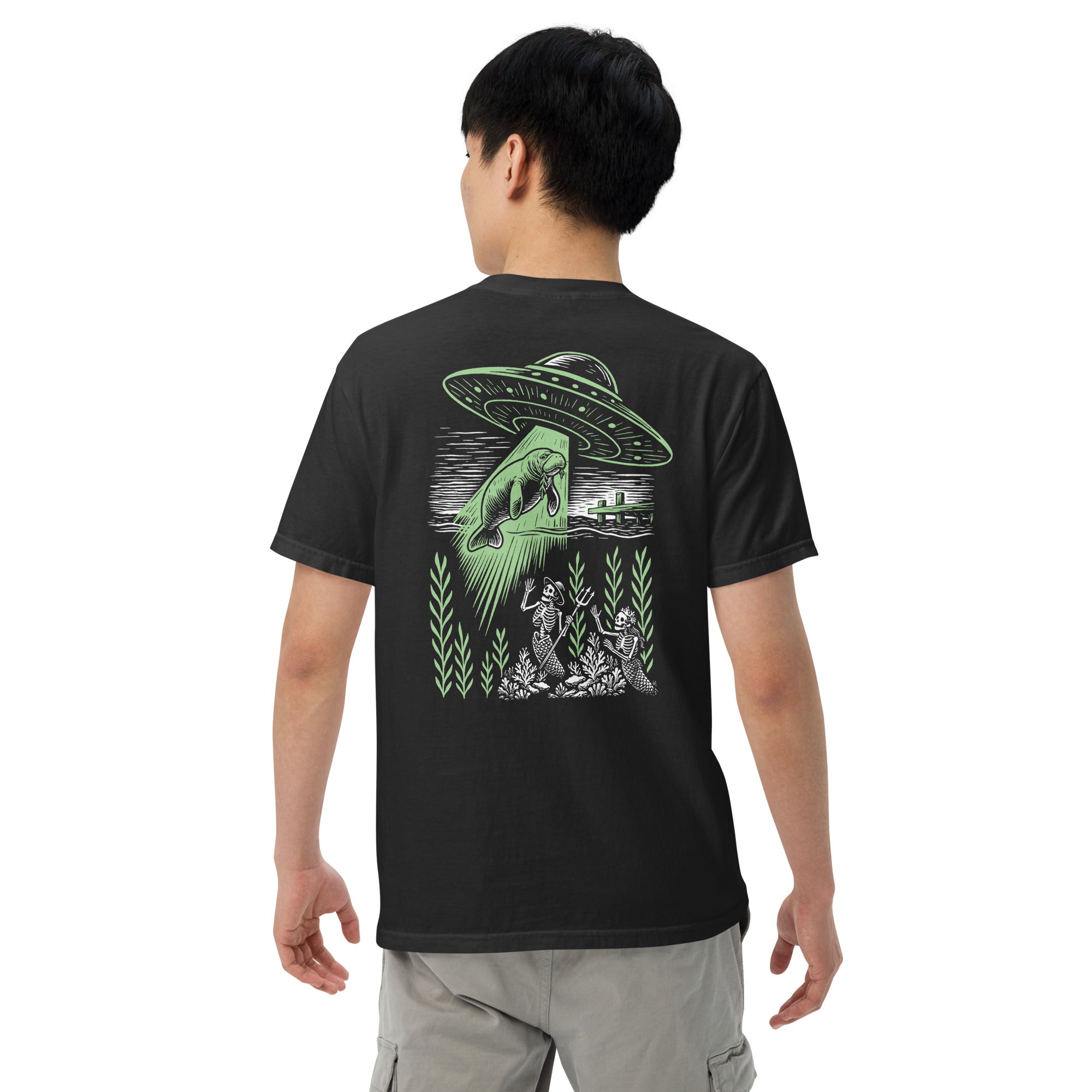 "Ocean Abduction" garment-dyed heavyweight tee, male model back view, featuring UFO abducting a manatee via tractor beam over skeleton mermaids design – 17th & Surf