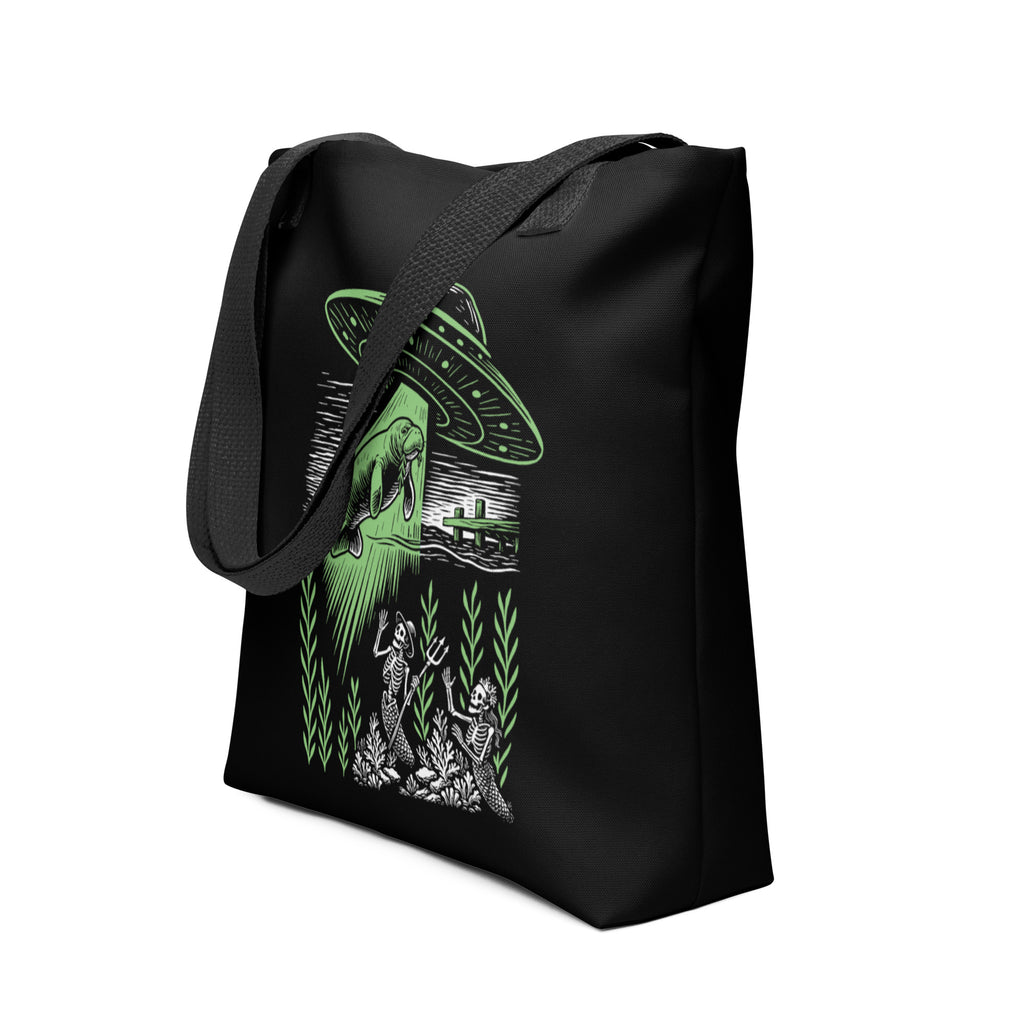 "Ocean Abduction" canvas tote bag, angled side view, featuring UFO abducting a manatee via tractor beam over skeleton mermaids design – 17th & Surf