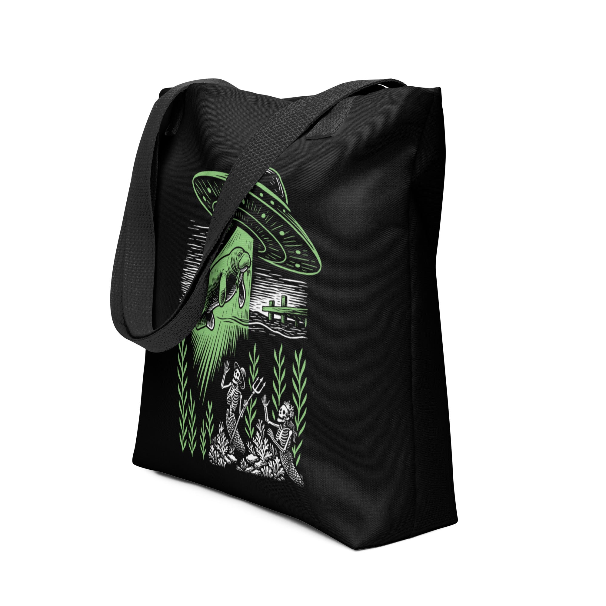 "Ocean Abduction" canvas tote bag, angled side view, featuring UFO abducting a manatee via tractor beam over skeleton mermaids design – 17th & Surf