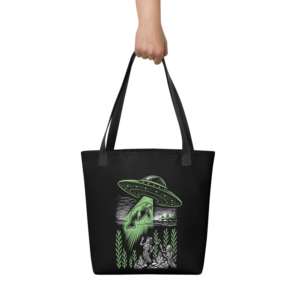 "Ocean Abduction" canvas tote bag, front view, featuring UFO abducting a manatee via tractor beam over skeleton mermaids design – 17th & Surf