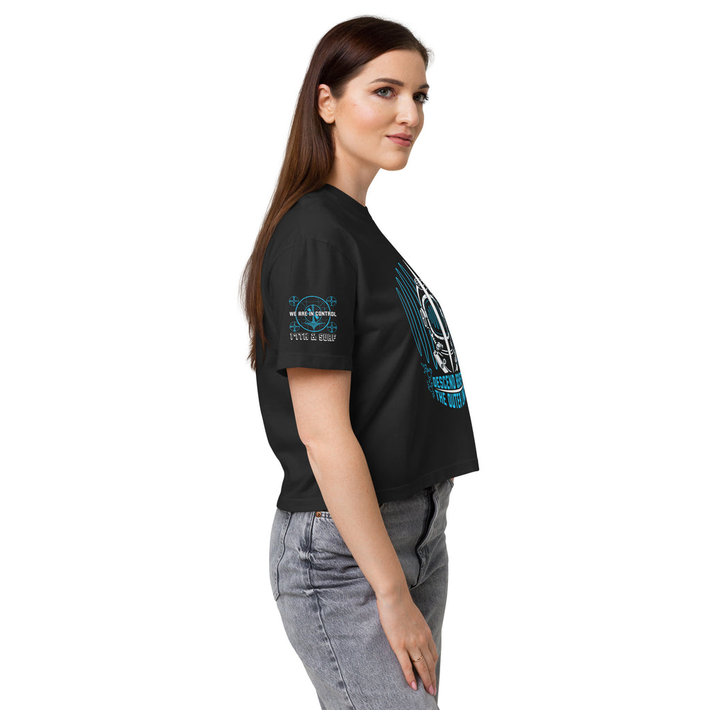 "Beneath The Outer Limits" women's heavyweight boxy tee in black, side profile view on female model, featuring the small "WE ARE IN CONTROL / 17th & Surf" sleeve logo and the large diving-helmet graphic – "Beneath The Outer Limits" Series by 17th & Surf