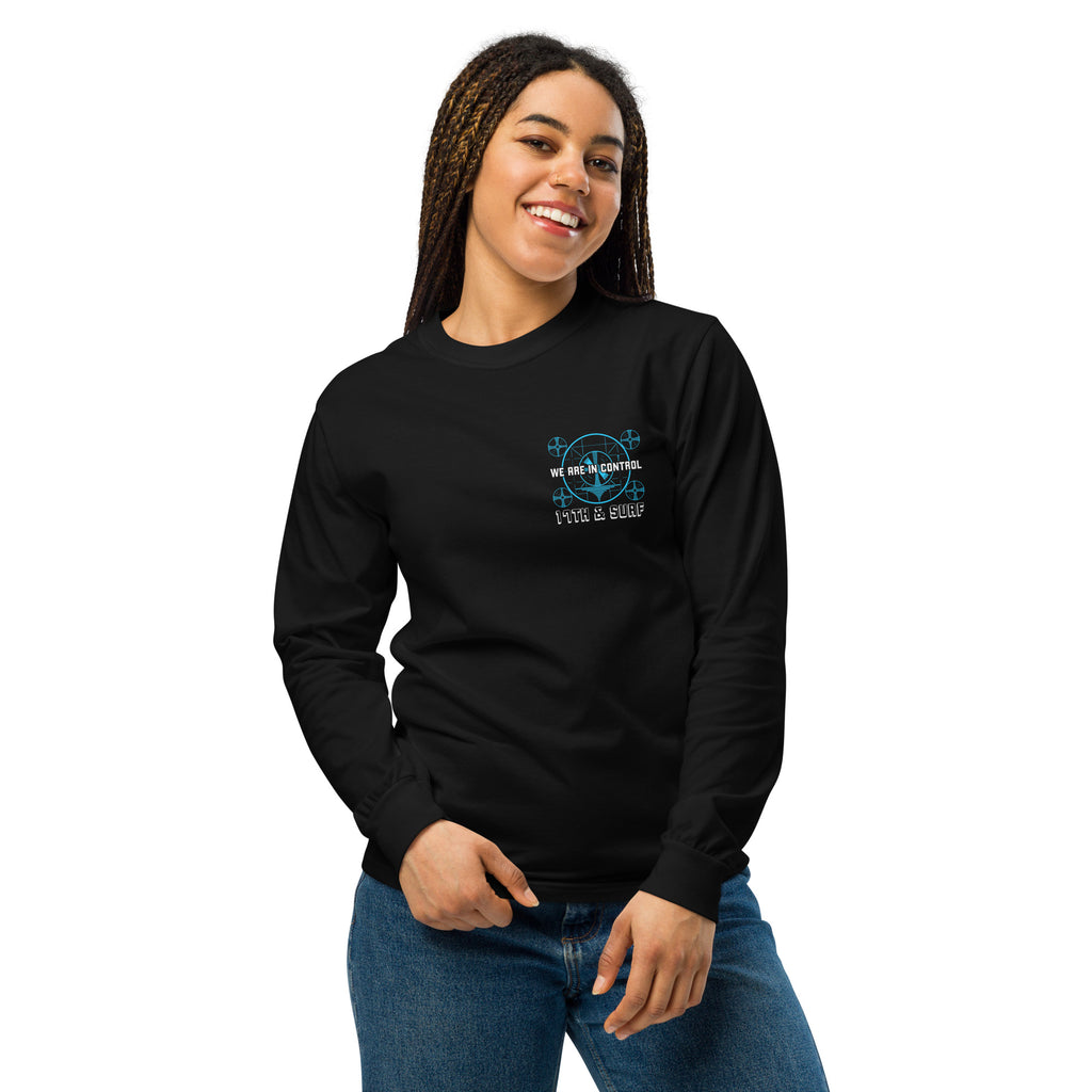 "Beneath The Outer Limits" garment-dyed heavyweight long sleeve shirt in black, front view on female model, featuring the small blue "WE ARE IN CONTROL" broadcast test-pattern chest logo with "17th & Surf" text – "Beneath The Outer Limits" Series by 17th & Surf