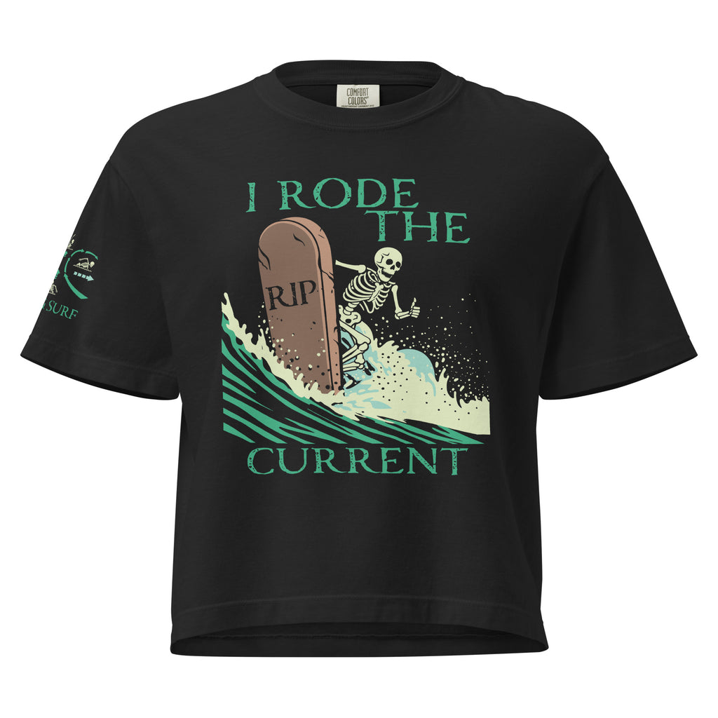 "RIP Current" women's heavyweight boxy tee in black, front view showing skeleton surfing a "RIP" tombstone "I Rode the Current" graphic and "17TH & SURF" sleeve emblem – 17th & Surf