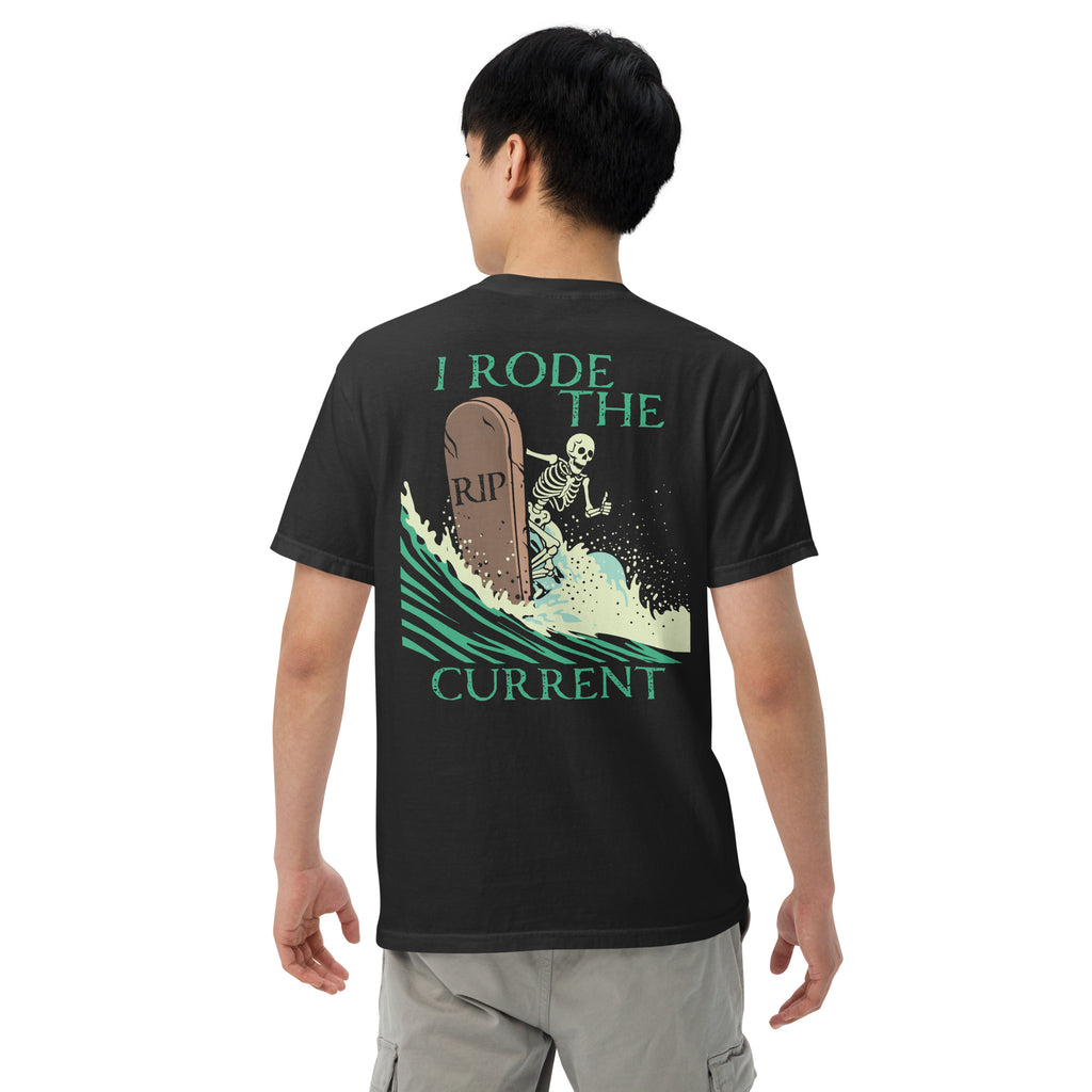 Model wearing "RIP Current" garment-dyed heavyweight tee in black, back view featuring skeleton surfing a "RIP" tombstone "I Rode the Current" graphic – 17th & Surf