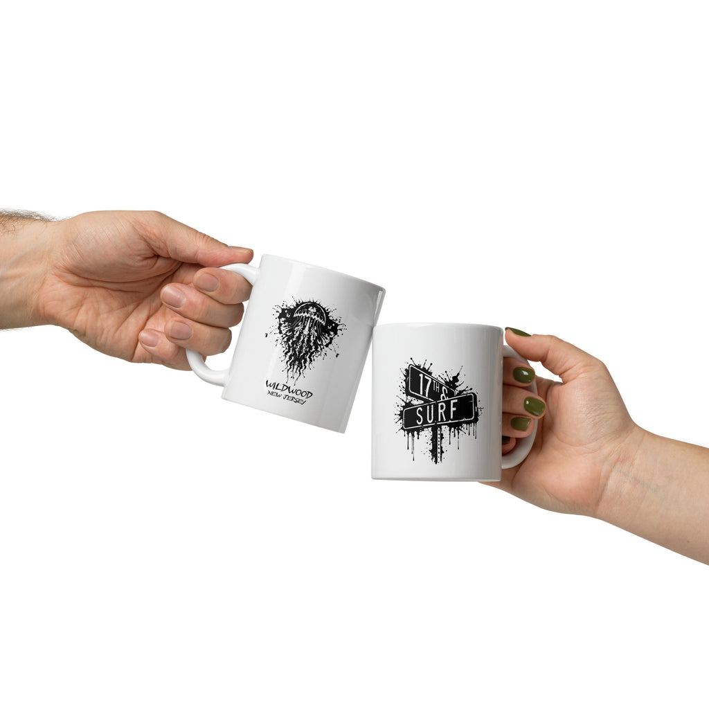 Rorschach Series Jellyfish 11oz mug pair held in hands showing black Rorschach ink-blot jellyfish design on one mug and small "17th & Surf" street sign logo on the other – 17th & Surf