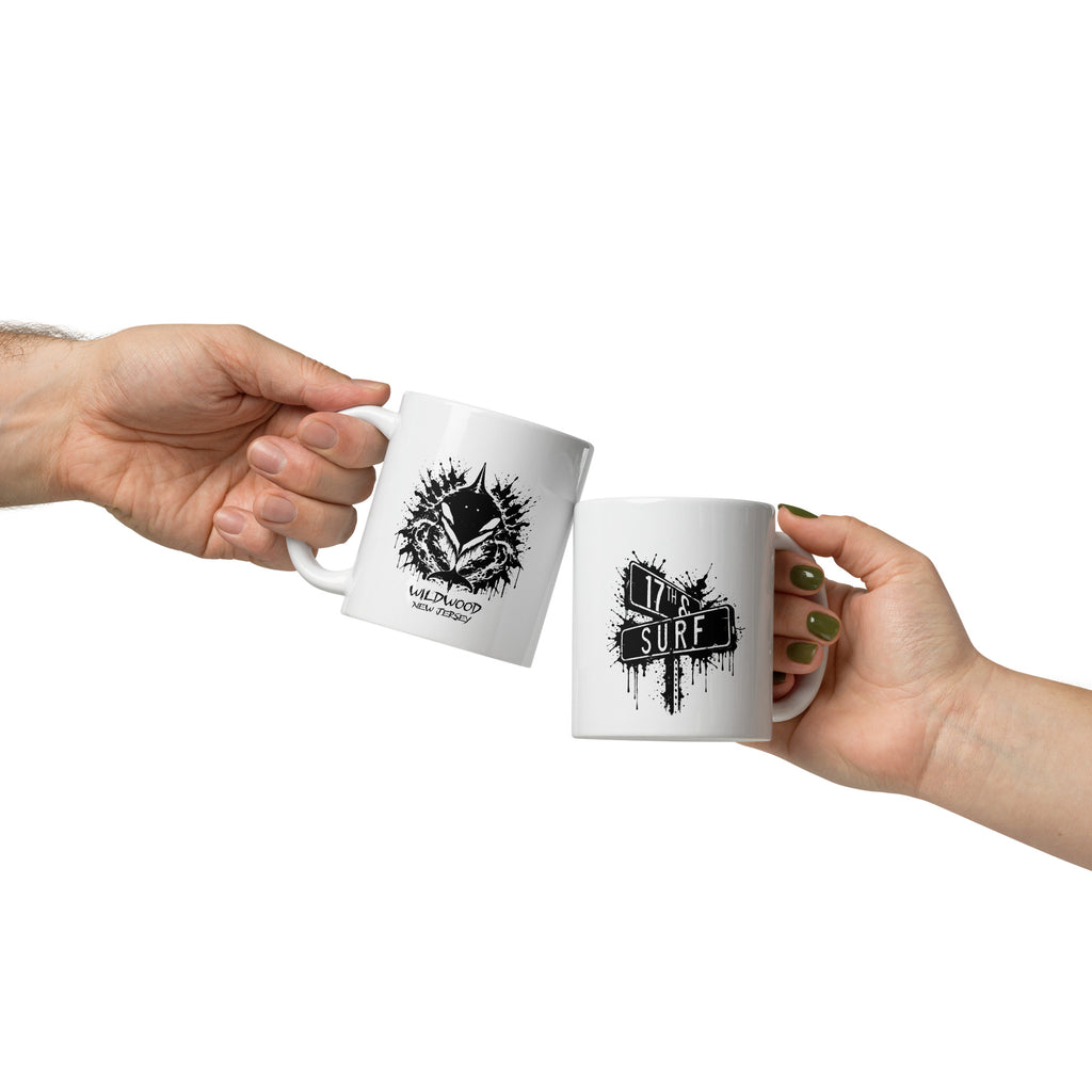 Rorschach Series Orca white glossy 11oz mug lifestyle cheers view showing black Rorschach ink-blot orca design with "Wildwood New Jersey" text and "17th & Surf" street sign logo on matching mugs – 17th & Surf