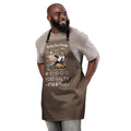 Model wearing "Salty Sea Dawg" chef apron featuring color graphic of a sea lion sprinkling salt on a clam shell with a fish skeleton beneath arched "Salty Sea Dawg" text and "TOO SALTY" one-star rating with "17th & Surf" wordmark, front view – 17th & Surf