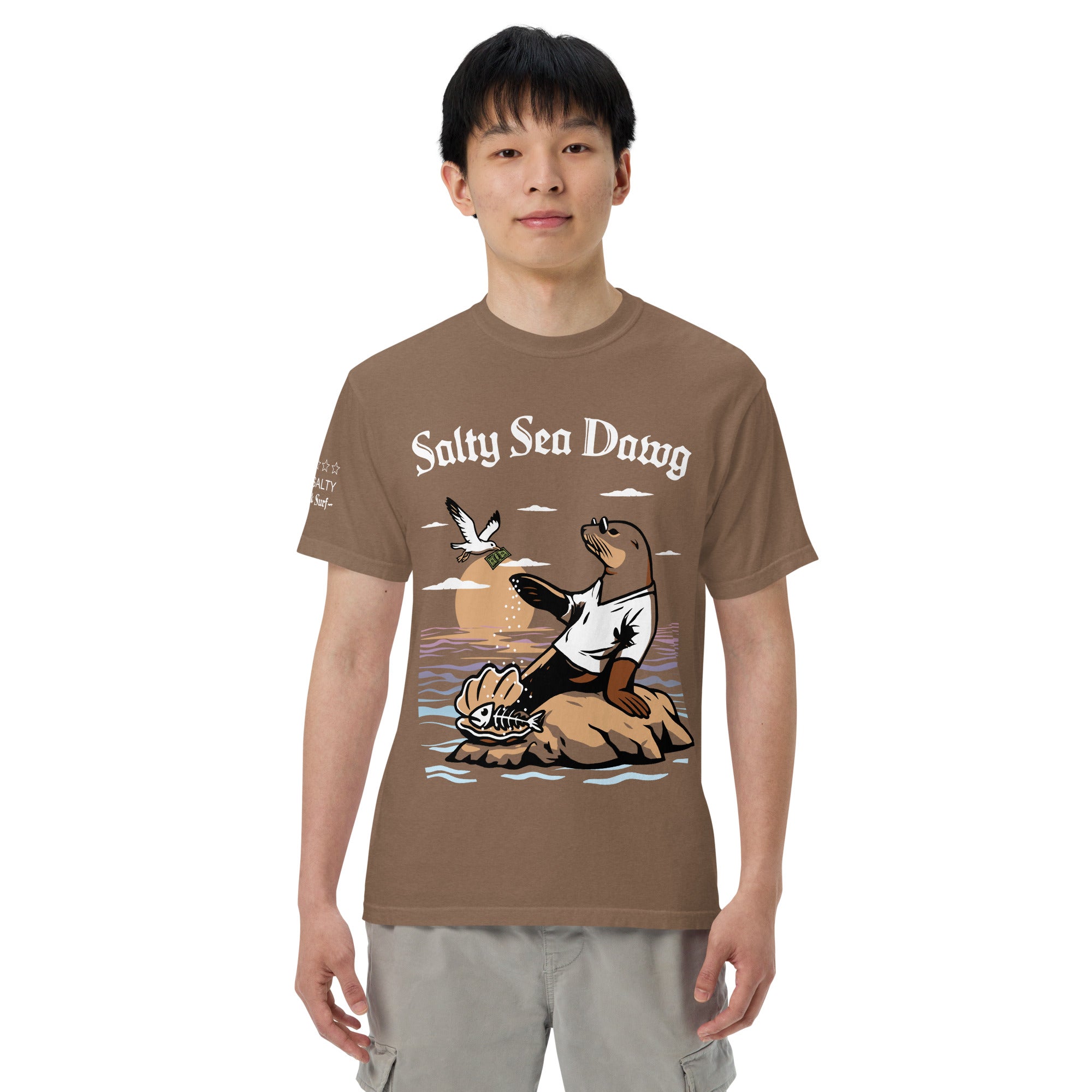 Model wearing "Salty Sea Dawg" front print garment-dyed heavyweight t-shirt in espresso, second front view featuring full color graphic of a sea lion sprinkling salt on a clam shell with a fish skeleton beneath arched "Salty Sea Dawg" text – 17th & Surf