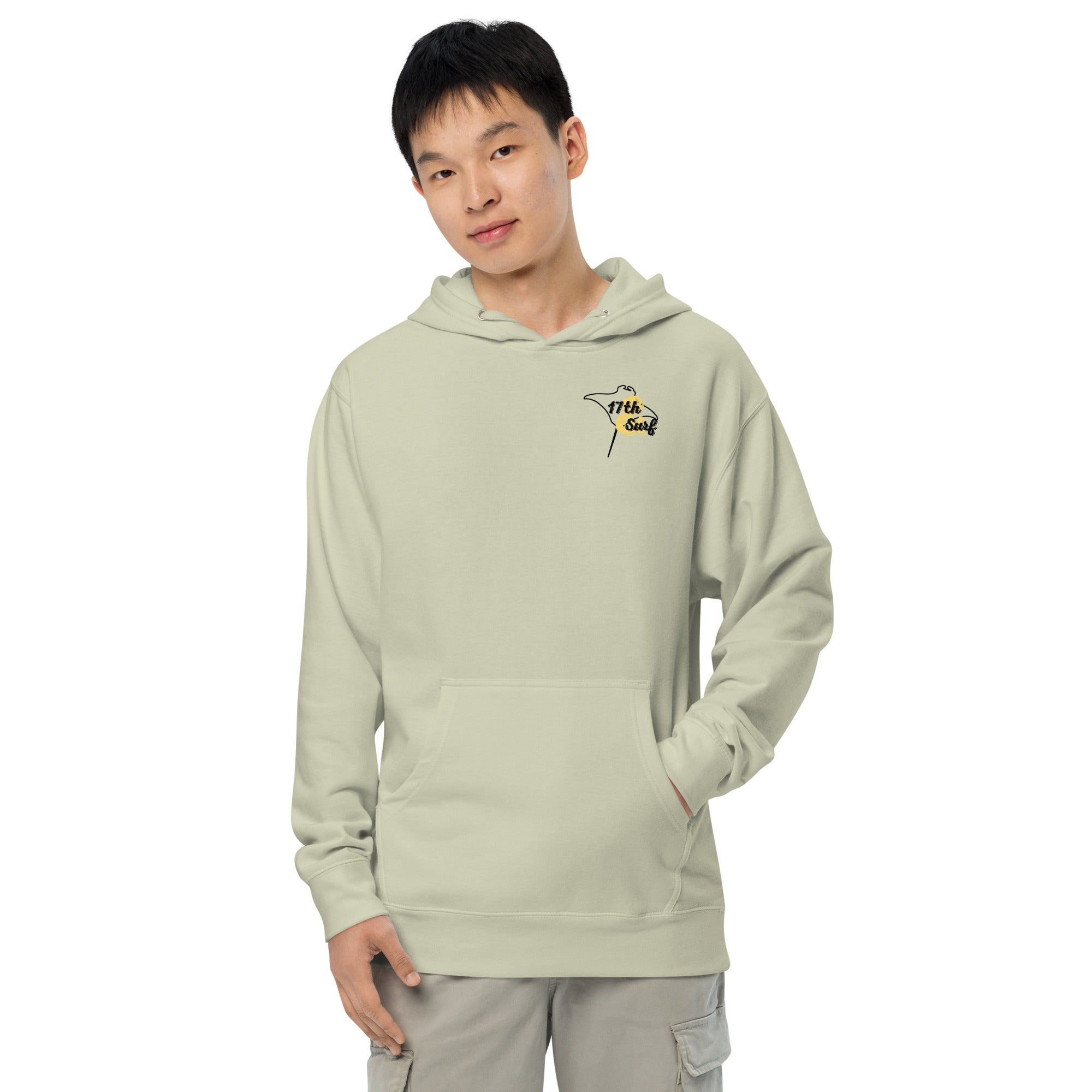 Model wearing "Resist The Siren's Call" garment-dyed heavyweight hoodie in dusty sage with black and yellow "17th & Surf" manta ray chest logo, front view – 17th & Surf