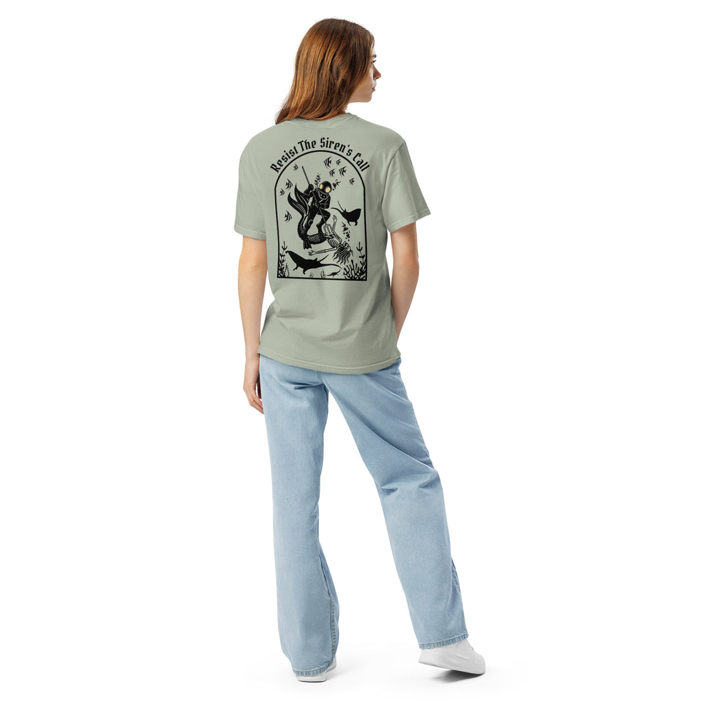 Model wearing "Resist The Siren's Call" black print garment-dyed heavyweight t-shirt in sage bay green, back angle view featuring black arched graphic of a deep-sea diver spearing a mermaid skeleton surrounded by fish and manta rays – 17th & Surf