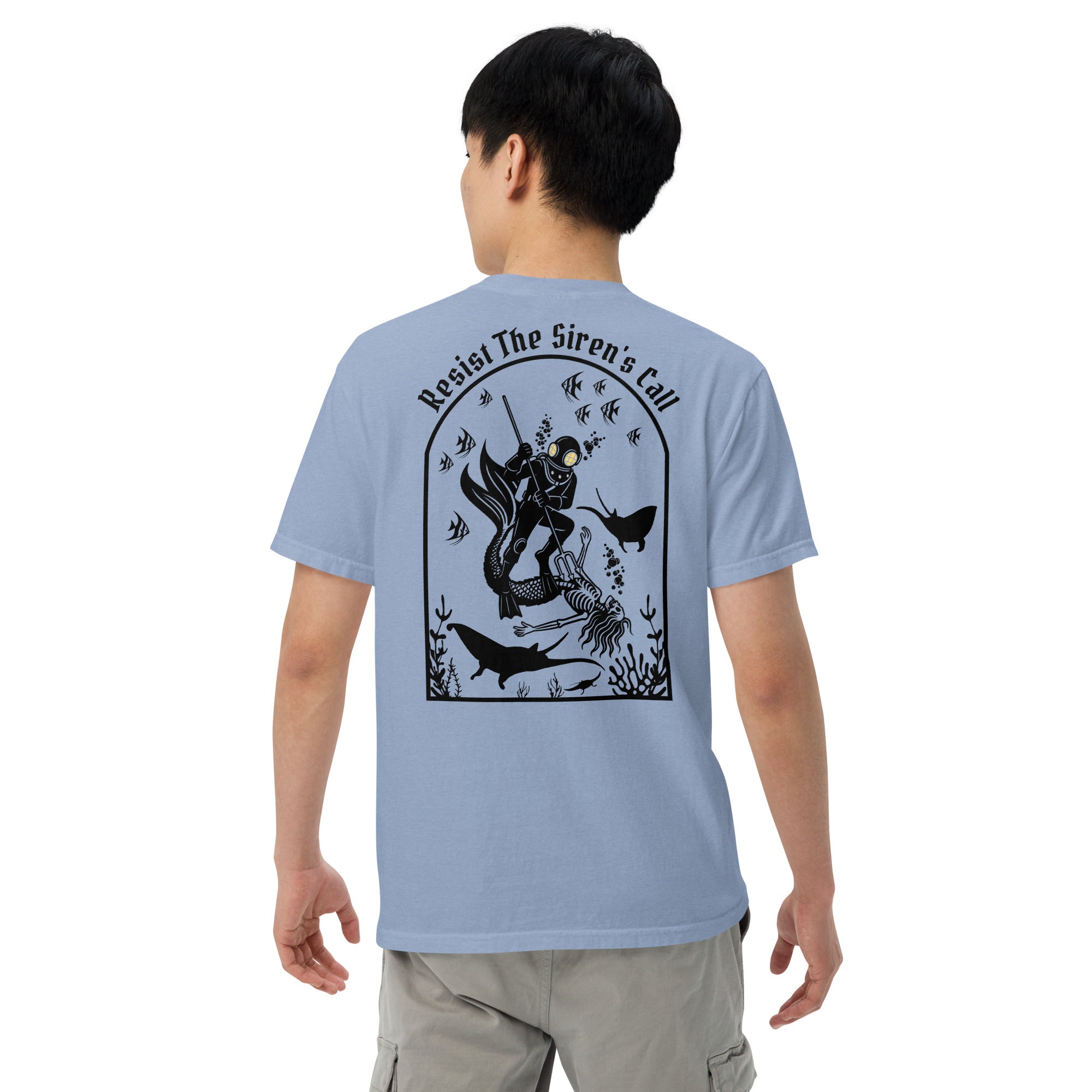 Model wearing "Resist The Siren's Call" black print garment-dyed heavyweight t-shirt in washed denim blue, back angle view featuring black arched graphic of a deep-sea diver spearing a mermaid skeleton surrounded by fish and manta rays – 17th & Surf