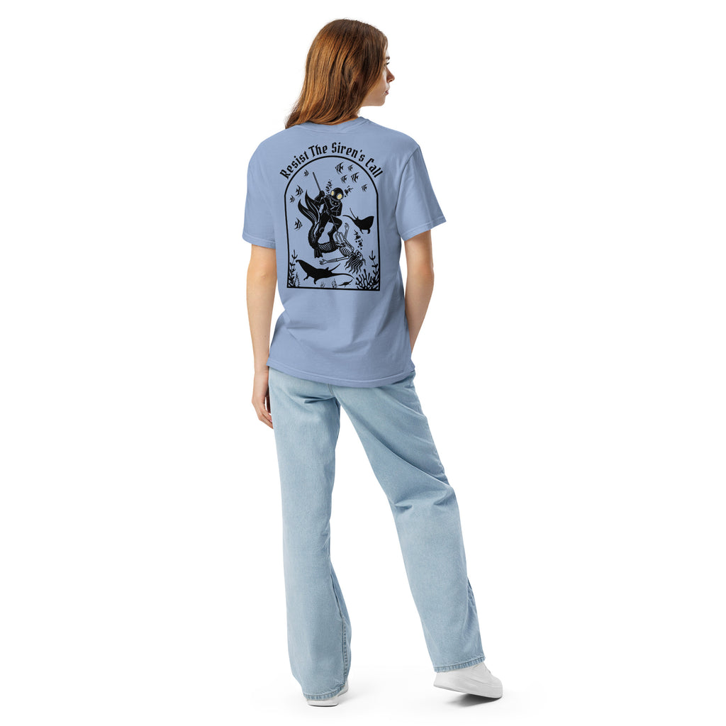 Model wearing "Resist The Siren's Call" black print garment-dyed heavyweight t-shirt in washed denim blue, back view featuring black arched graphic of a deep-sea diver spearing a mermaid skeleton surrounded by fish and manta rays – 17th & Surf