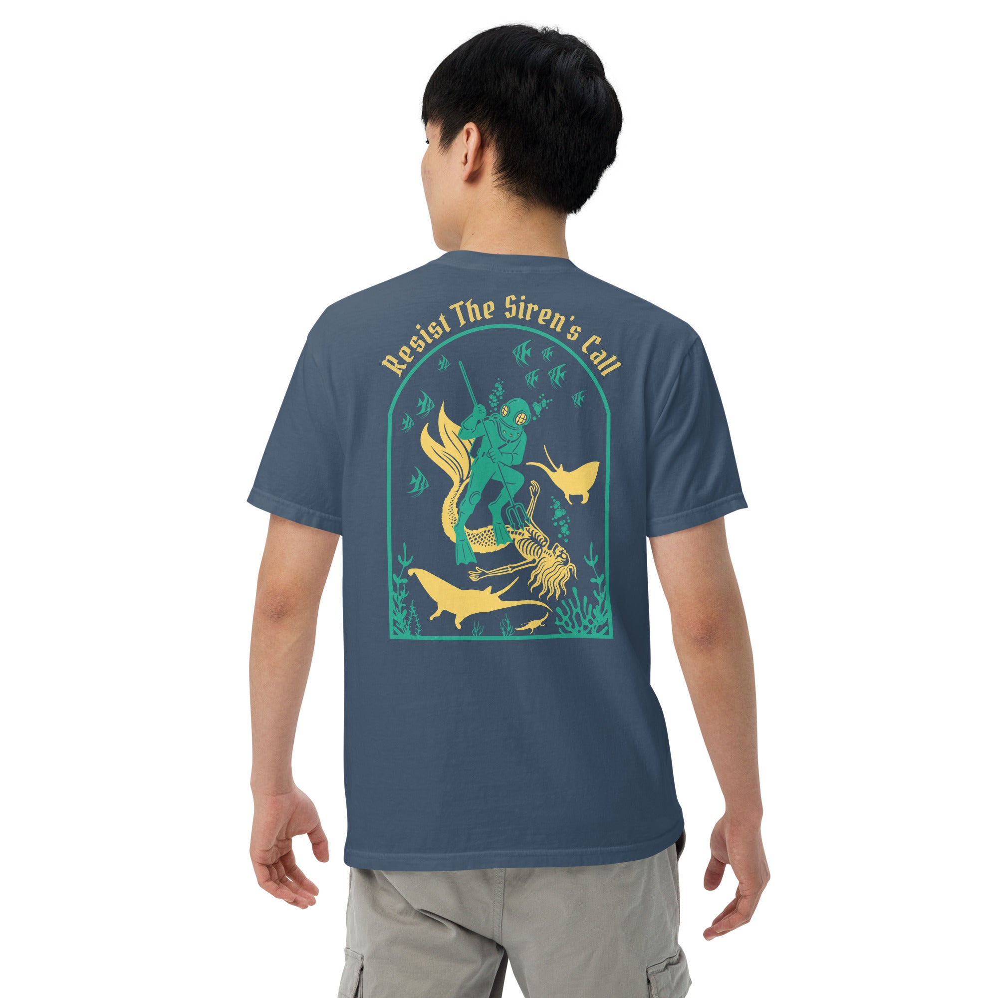 Model wearing "Resist The Siren's Call" color print garment-dyed heavyweight t-shirt in midnight, back second angle view featuring teal and yellow arched graphic of a deep-sea diver spearing a mermaid skeleton surrounded by fish and manta rays – 17th & Surf