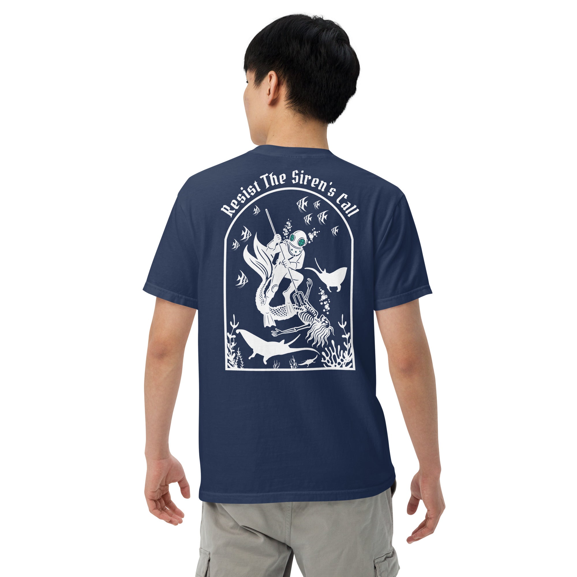 Model wearing "Resist The Siren's Call" white print garment-dyed heavyweight t-shirt in true navy, back view featuring white arched graphic of a deep-sea diver spearing a mermaid skeleton surrounded by fish and manta rays – 17th & Surf