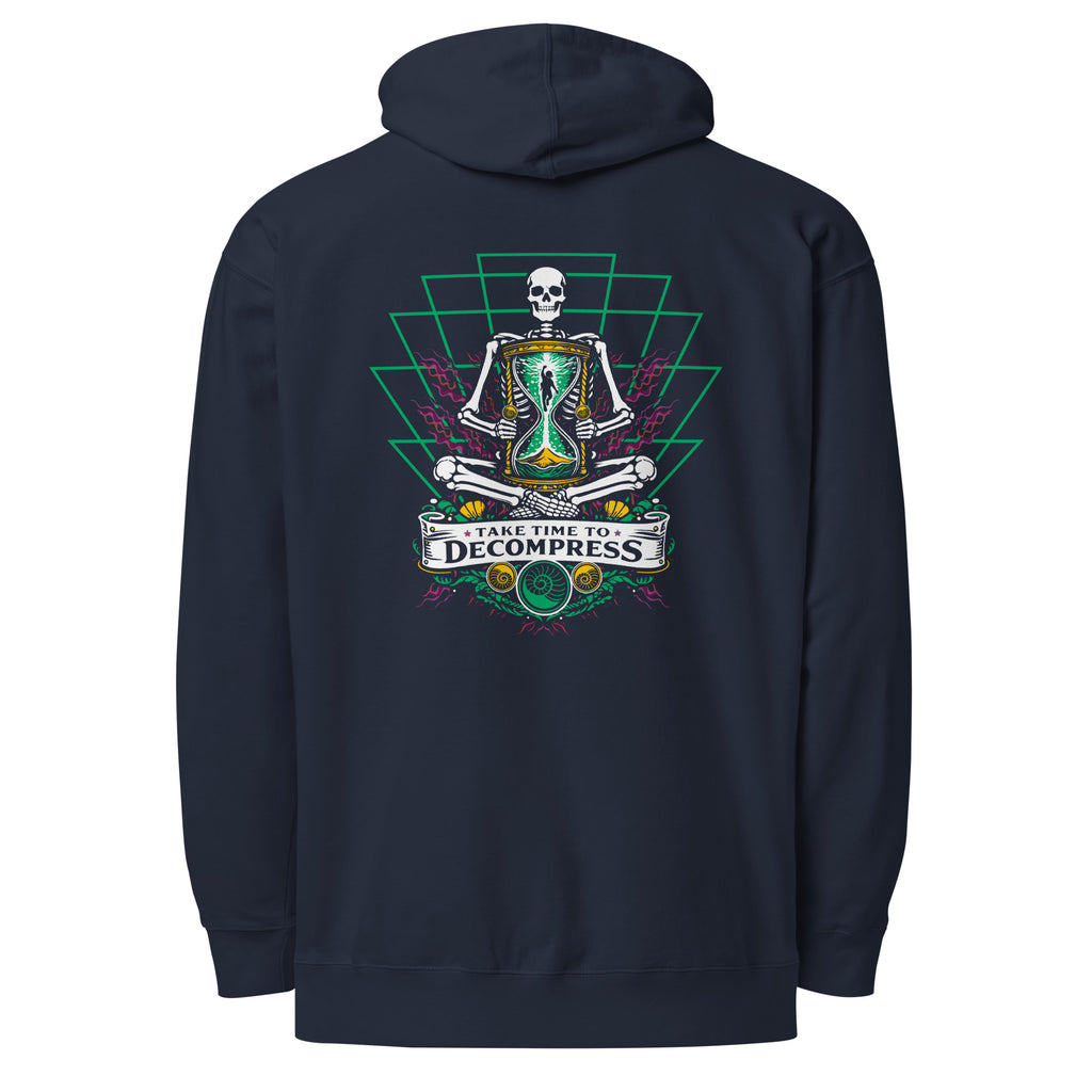 "Take Time To Decompress" classic navy midweight hoodie, back flat lay, featuring a meditating skeleton holding a glowing hourglass with a tiny silhouette inside, framed by a green geometric pyramid pattern with purple coral accents and gold ammonite shells, above a "Take Time To Decompress" banner – 17th & Surf