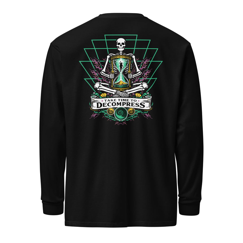 "Take Time To Decompress" black heavyweight long sleeve shirt, back flat lay, featuring a meditating skeleton holding a glowing hourglass with a tiny silhouette inside, framed by a green geometric pyramid pattern with purple coral accents and gold ammonite shells, above a "Take Time To Decompress" banner – 17th & Surf