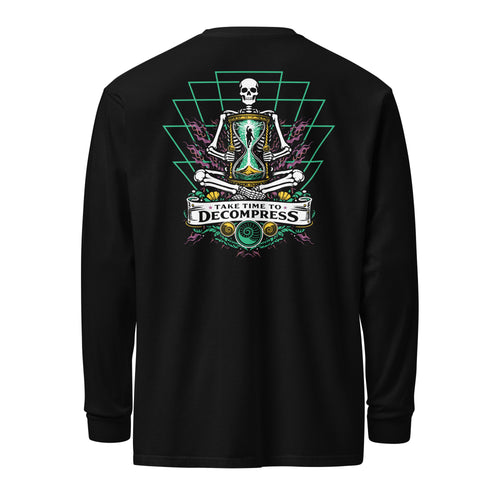 "Take Time To Decompress" black heavyweight long sleeve shirt, back flat lay, featuring a meditating skeleton holding a glowing hourglass with a tiny silhouette inside, framed by a green geometric pyramid pattern with purple coral accents and gold ammonite shells, above a "Take Time To Decompress" banner – 17th & Surf
