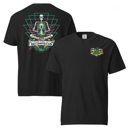 "Take Time To Decompress" black heavyweight t-shirt, flat lay showing both front and back, featuring a small gold and teal "17th & Surf" hourglass logo on the left chest and the full meditating skeleton design with glowing hourglass on the back, framed by a green geometric pyramid pattern with purple coral accents and gold ammonite shells above a "Take Time To Decompress" banner – 17th & Surf