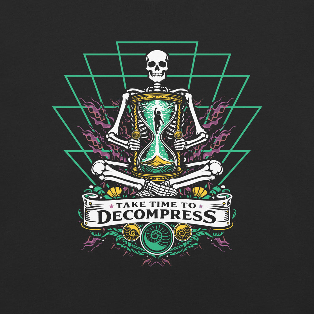 "Take Time To Decompress" black heavyweight t-shirt, close-up front flat lay on a dark background, featuring a meditating skeleton holding a glowing hourglass with a tiny silhouette inside, framed by a green geometric pyramid pattern with purple coral accents and gold ammonite shells, above a "Take Time To Decompress" banner – 17th & Surf