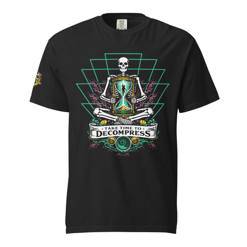 "Take Time To Decompress" black heavyweight t-shirt, front flat lay, featuring a meditating skeleton holding a glowing hourglass with a tiny silhouette inside, framed by a green geometric pyramid pattern with purple coral accents and gold ammonite shells, above a "Take Time To Decompress" banner, with a small gold and teal "17th & Surf" hourglass logo on the left sleeve – 17th & Surf