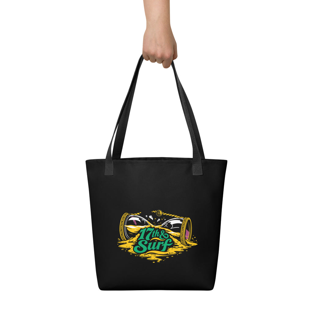 "Take Time To Decompress" black tote bag, held by model from behind showing the back panel featuring a gold and teal "17th & Surf" hourglass logo – 17th & Surf