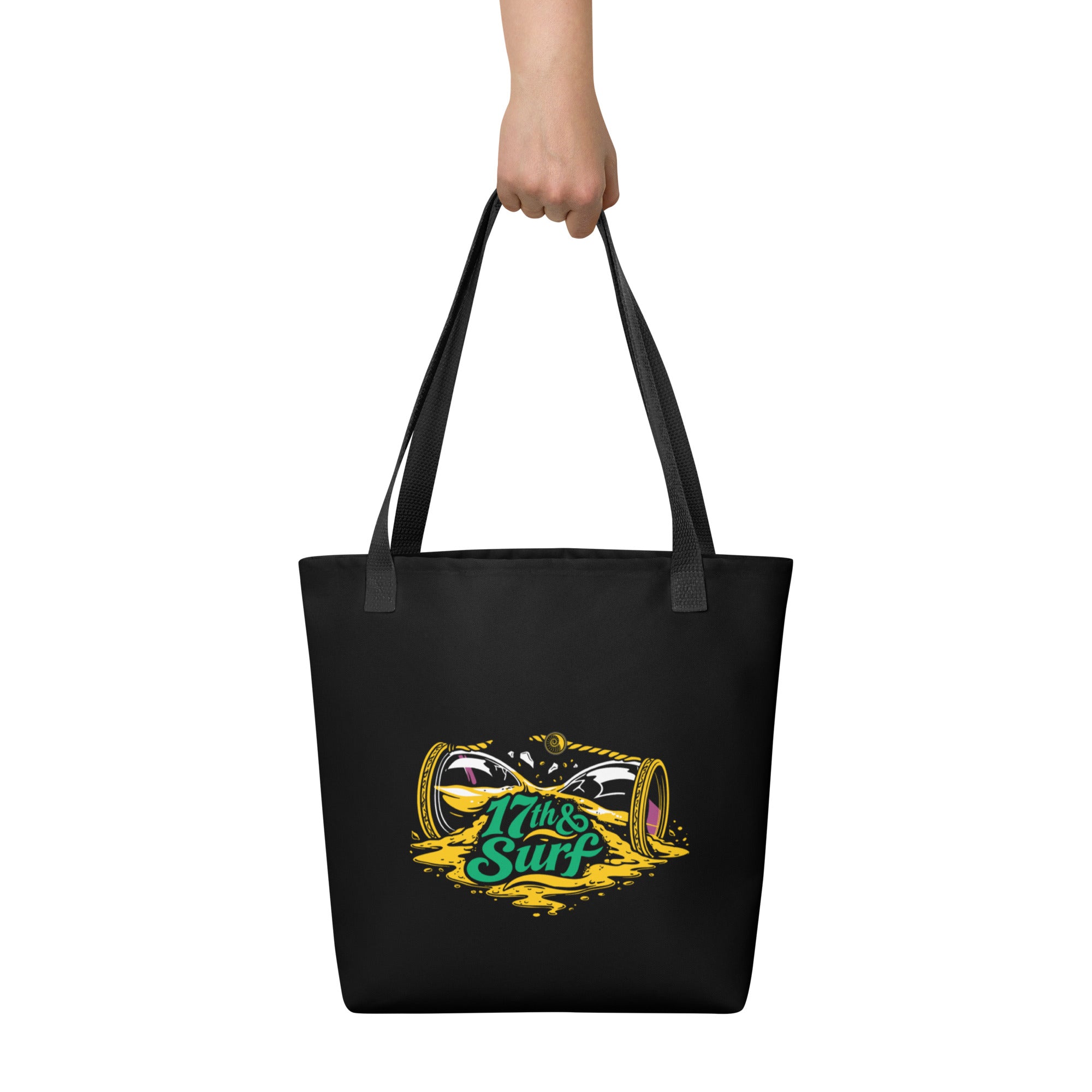 "Take Time To Decompress" black tote bag, held by model from behind showing the back panel featuring a gold and teal "17th & Surf" hourglass logo – 17th & Surf