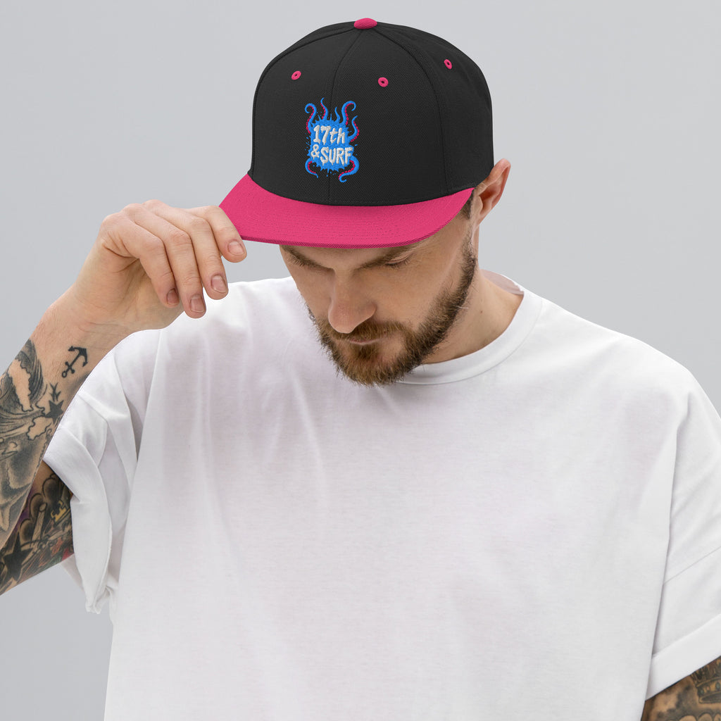 Model wearing the 17th & Surf Tentacles snapback hat, black and neon pink with a blue and pink tentacle-themed "17th & Surf" logo – 17th & Surf