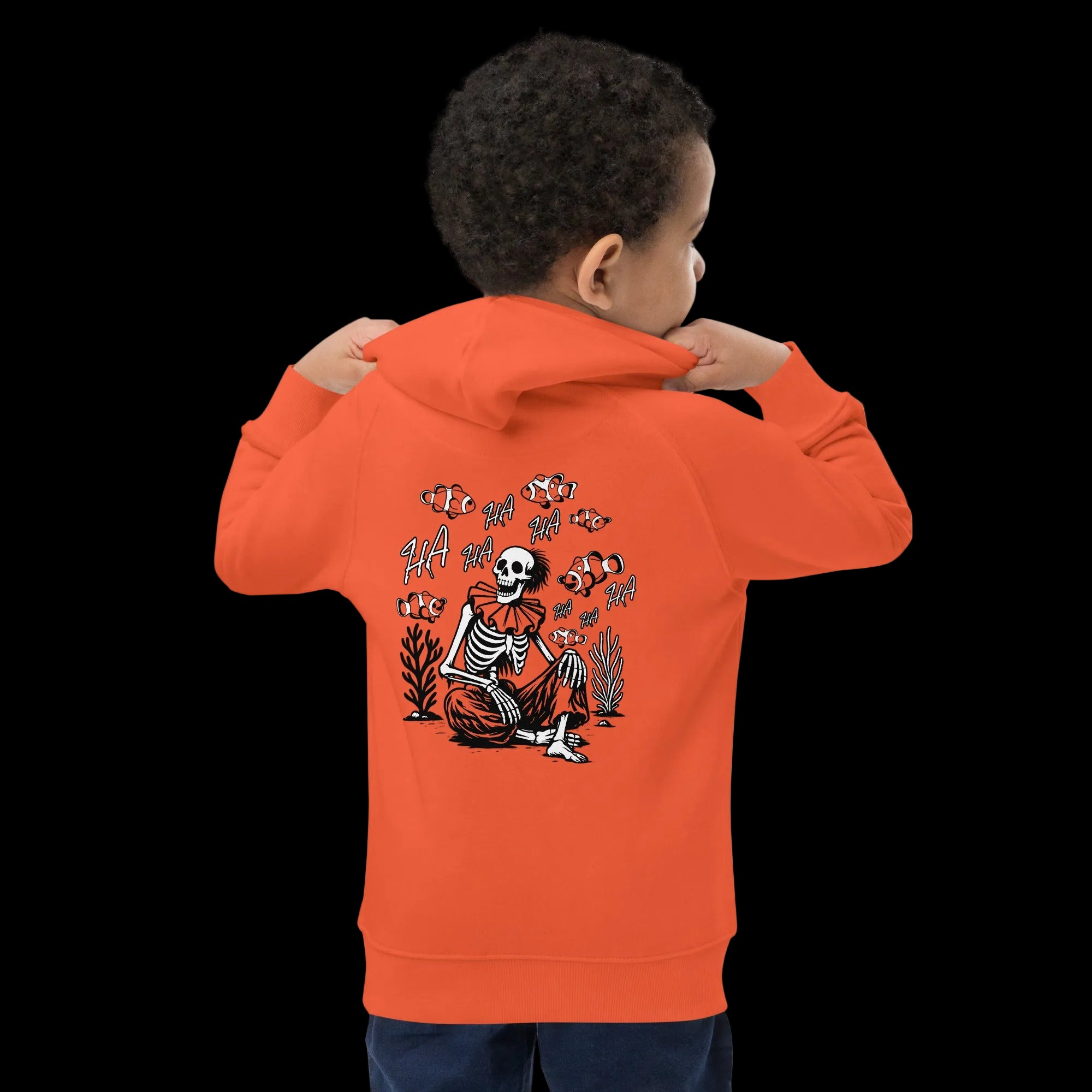 Boy wearing 17th & Surf burnt orange kids hoodie back view featuring I Started A Joke skeleton clown and clownfish graphic with “HA HA” text