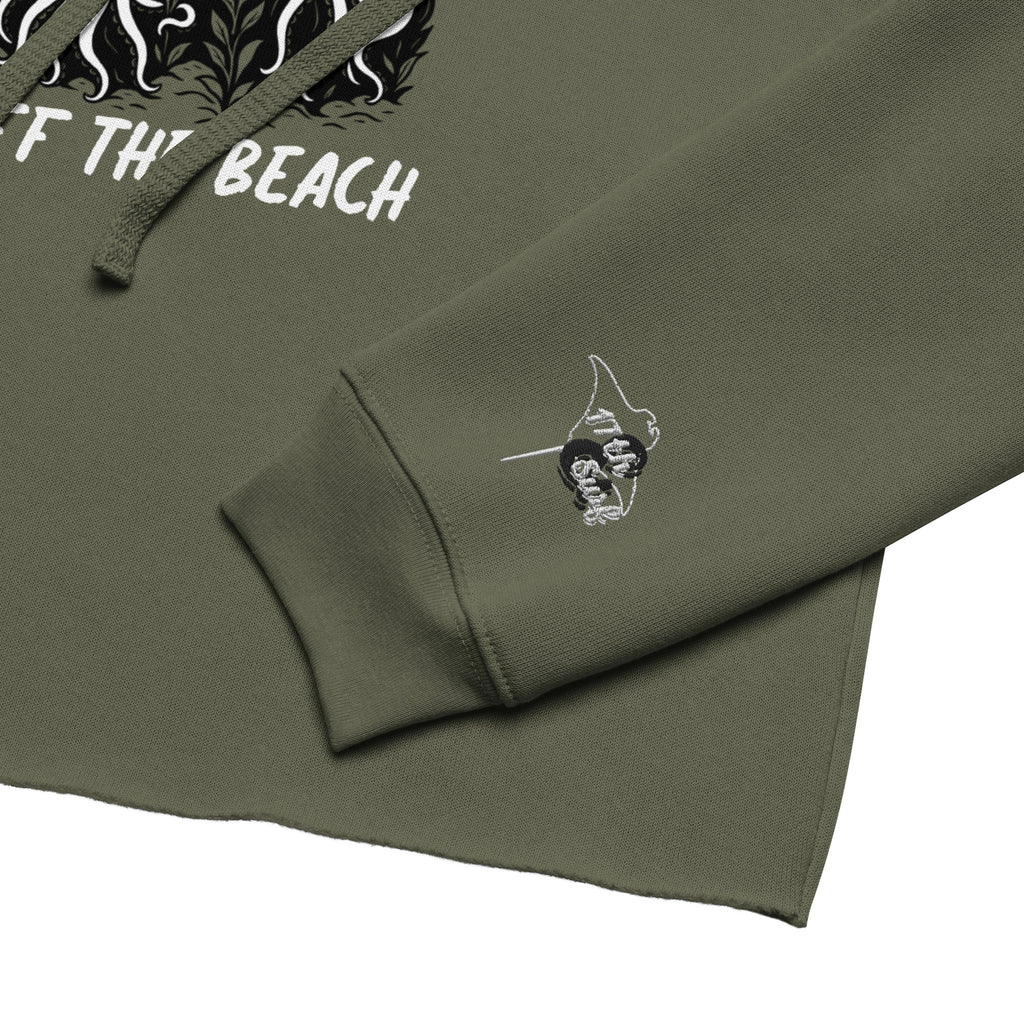 Close-up of military green cropped hoodie with embroidered 17th & Surf Stingray Logo on the sleeve and with the front print smoking skeleton and puffin in the background