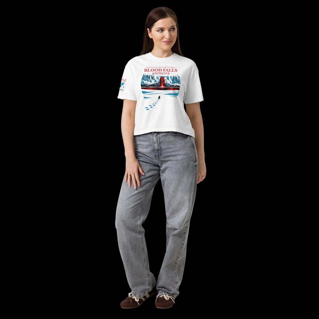 Full-body model wearing white women’s heavyweight boxy t-shirt with Blood Falls Antarctica design with lone penguin approaching the red waterfall and haunted seas sleeve patch